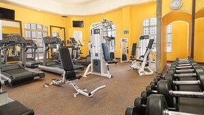 Una palestra con macchinari cardio, attrezzature per sollevamento pesi e uno specchio.