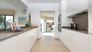 A modern kitchen with white cabinets, a stainless steel sink, and a view to a dining area. - Modern and nice villa  with private pool in Benissa, Costa Blanca, Spain for 6 persons (Benissa)