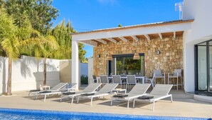 A poolside area with lounge chairs, a stone wall, and a covered seating area. - Modern and nice villa  with private pool in Benissa, Costa Blanca, Spain for 6 persons (Benissa)
