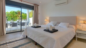 A spacious bedroom with a large bed, a sliding glass door leading to an outdoor dining area, and a modern air conditioning unit on the wall. - Modern and nice villa  with private pool in Benissa, Costa Blanca, Spain for 6 persons (Benissa)