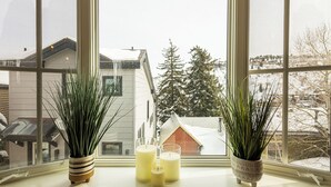 Uma janela com duas plantas em vasos e três velas no parapeito.