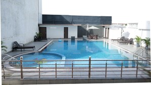 Una piscina interior con solárium de baldosas, sillas de descanso y una zona de estar cubierta.
