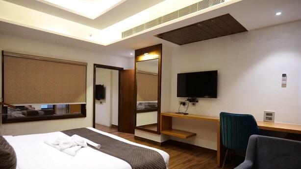 Una habitación de hotel con cama, escritorio, silla, televisión y espejo.