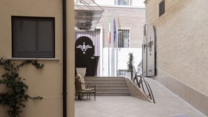 An outdoor area with a bench, a staircase, and a door with a decorative emblem. - Palazzo Sant'Elena (Foggia)