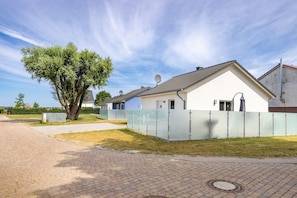 A residential building with a tiled roof, satellite dishes, and a fenced yard.