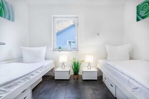Ein Doppelzimmer mit zwei Betten, Nachttischen mit Lampen, einem Fenster mit Blick und einer Zimmerpflanze.