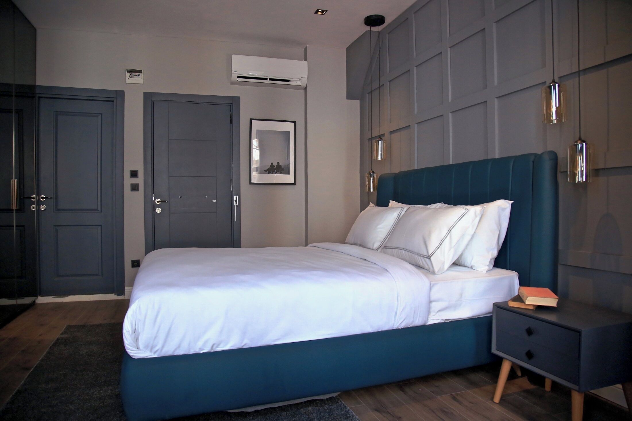 Ein modernes Schlafzimmer mit Bett, Nachttisch, Kleiderschrank und Klimaanlage.
