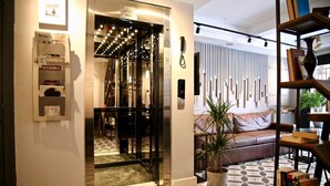 A hotel lobby with a patterned floor, a leather sofa, a bookshelf, and a reception area with a phone and a sign. - Hotel Bronte (Istanbul)