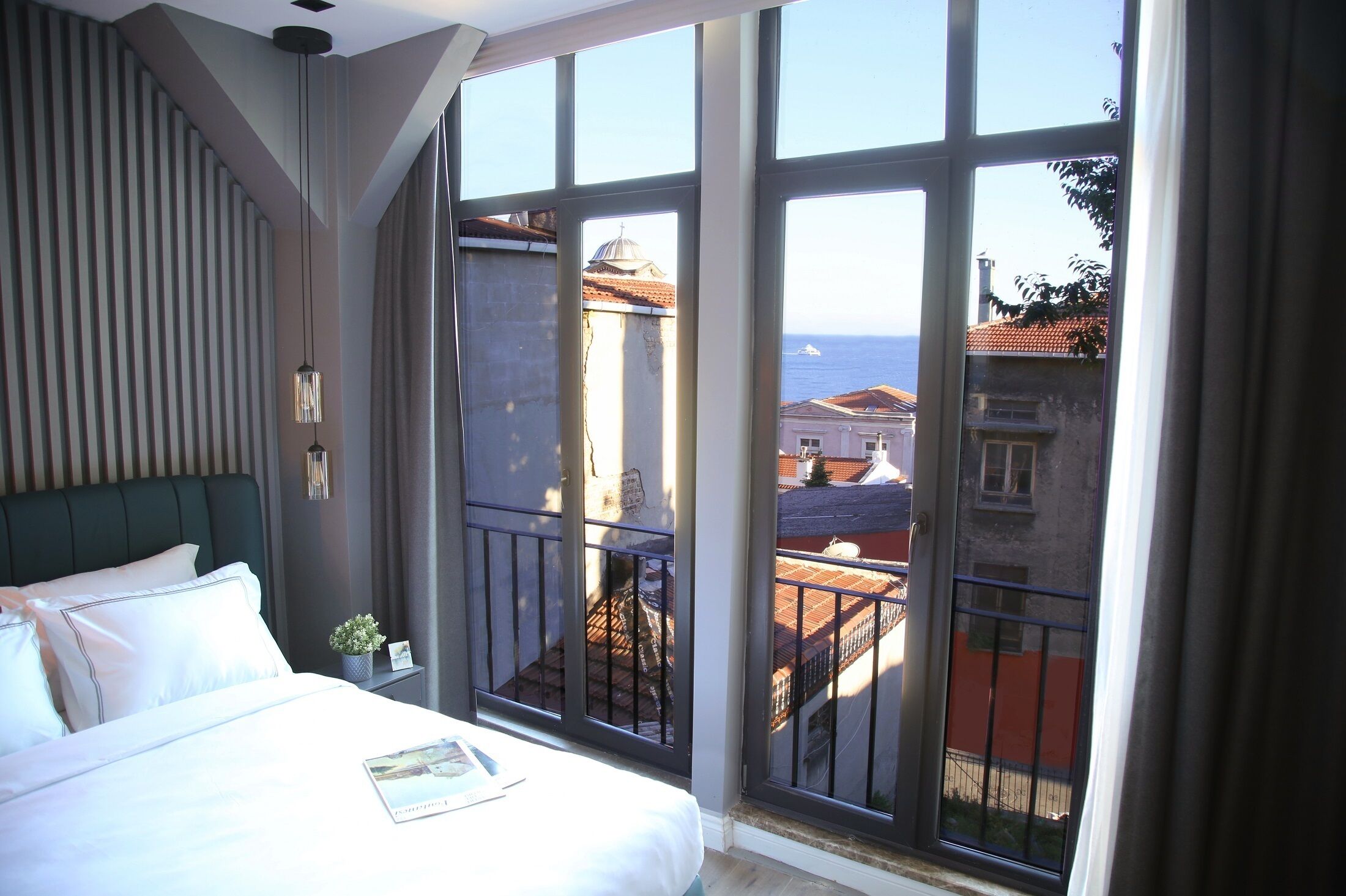 Habitación de hotel con una cama grande, vista al mar y un balcón con barandilla.