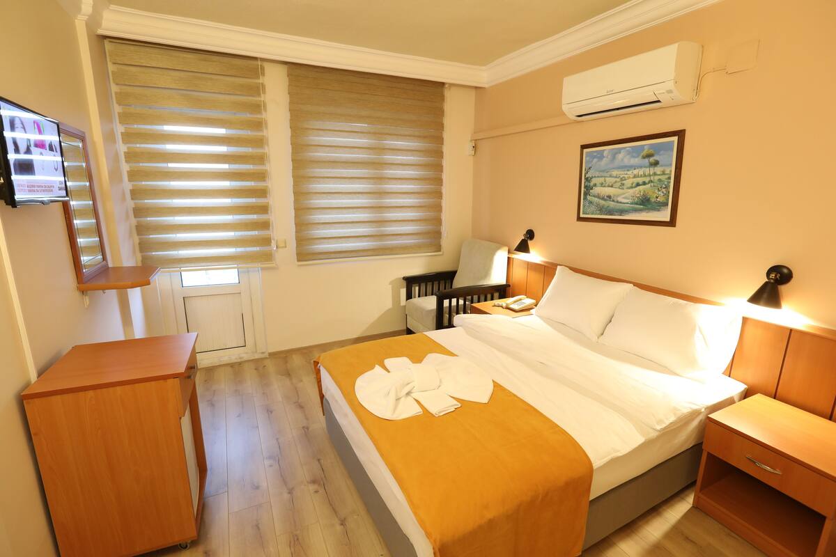 Une chambre d’hôtel équipée d’un lit, d’une table de chevet, d’une lampe et d’un téléviseur fixé au mur.