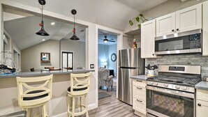 Una cocina moderna con armarios blancos, electrodomésticos de acero inoxidable y dos taburetes de bar.