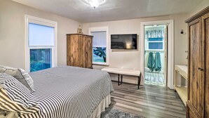 Un dormitorio con cama, un armario de madera, una banca y vistas al exterior.