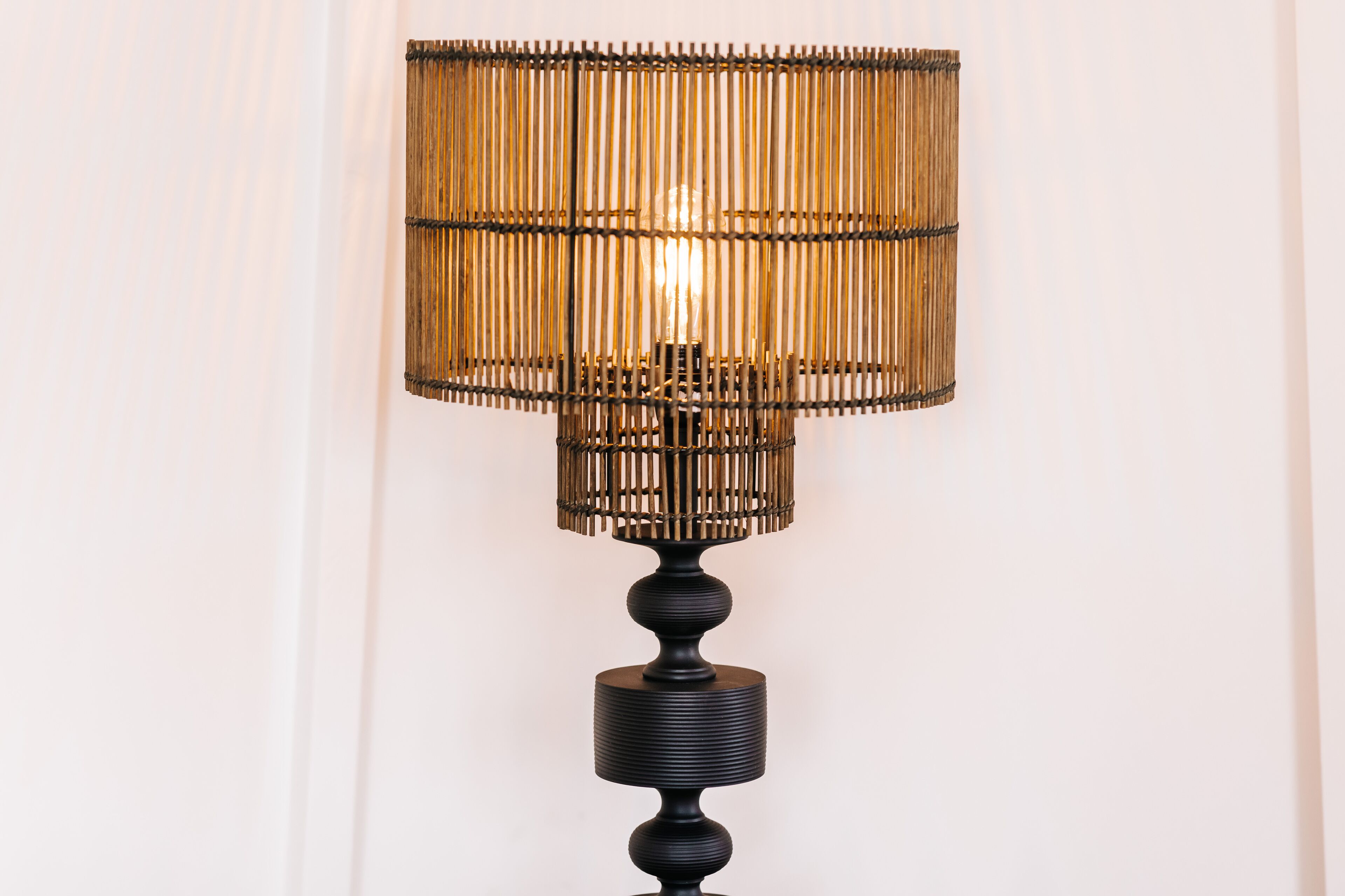 A black table lamp with a cylindrical base and a woven shade.