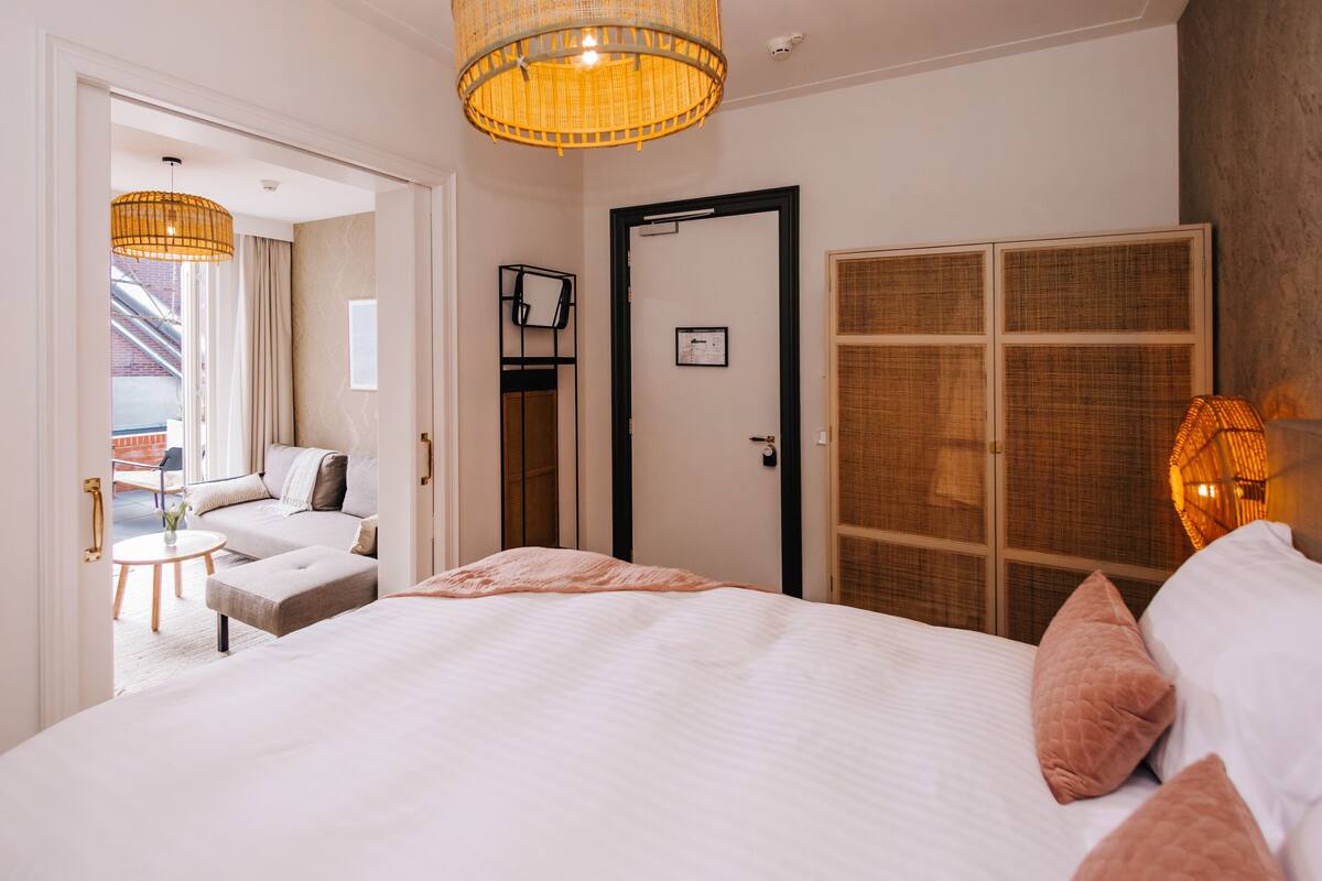 Habitación de hotel con cama, sofá, una mesita, una puerta y vistas al exterior.