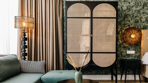 A modern living room with a sofa, a round coffee table, and a decorative wall panel. - Boutique hotel Margretha (Zandvoort)