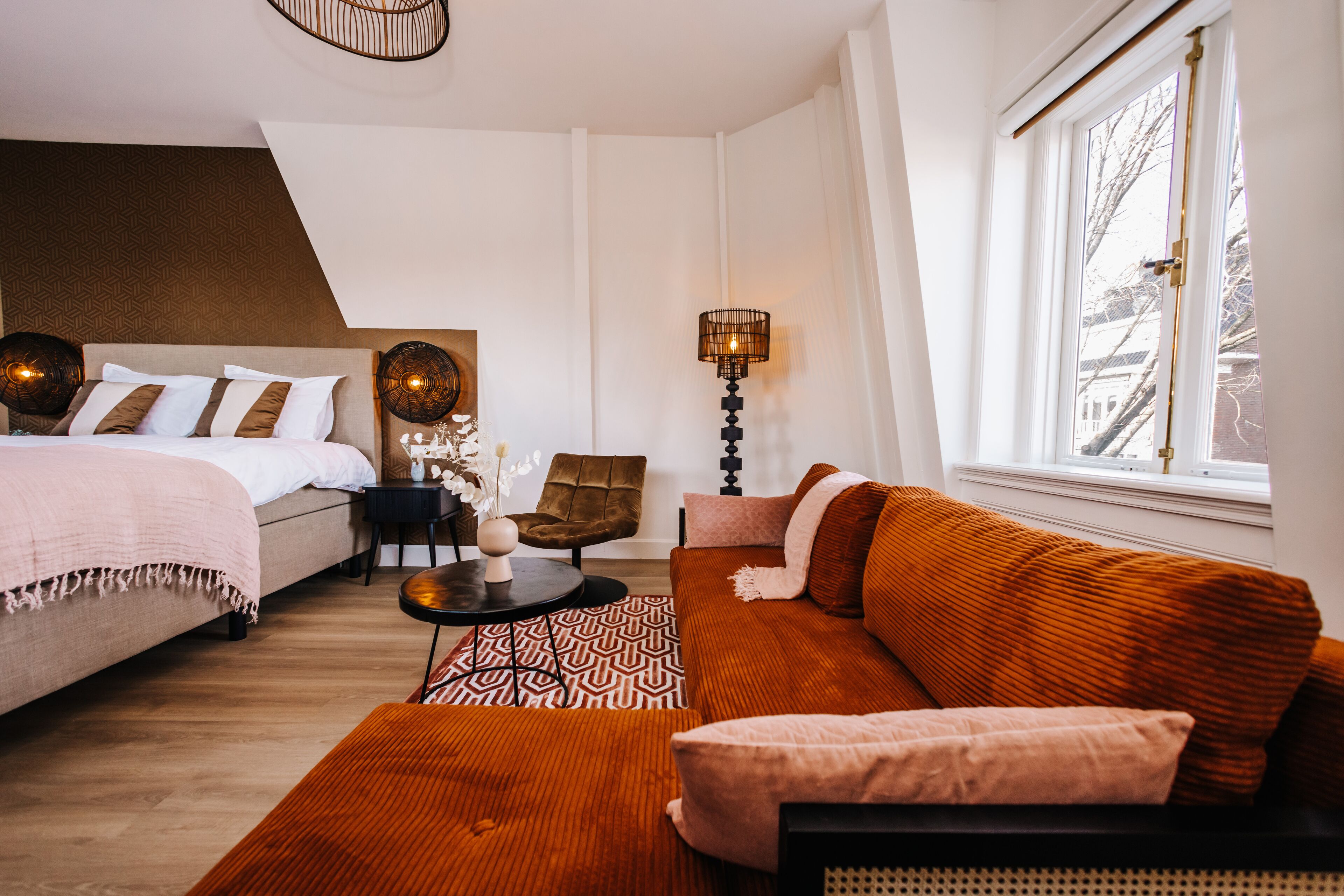 Una habitación de hotel moderna con cama, sofá, sillón y lámpara.