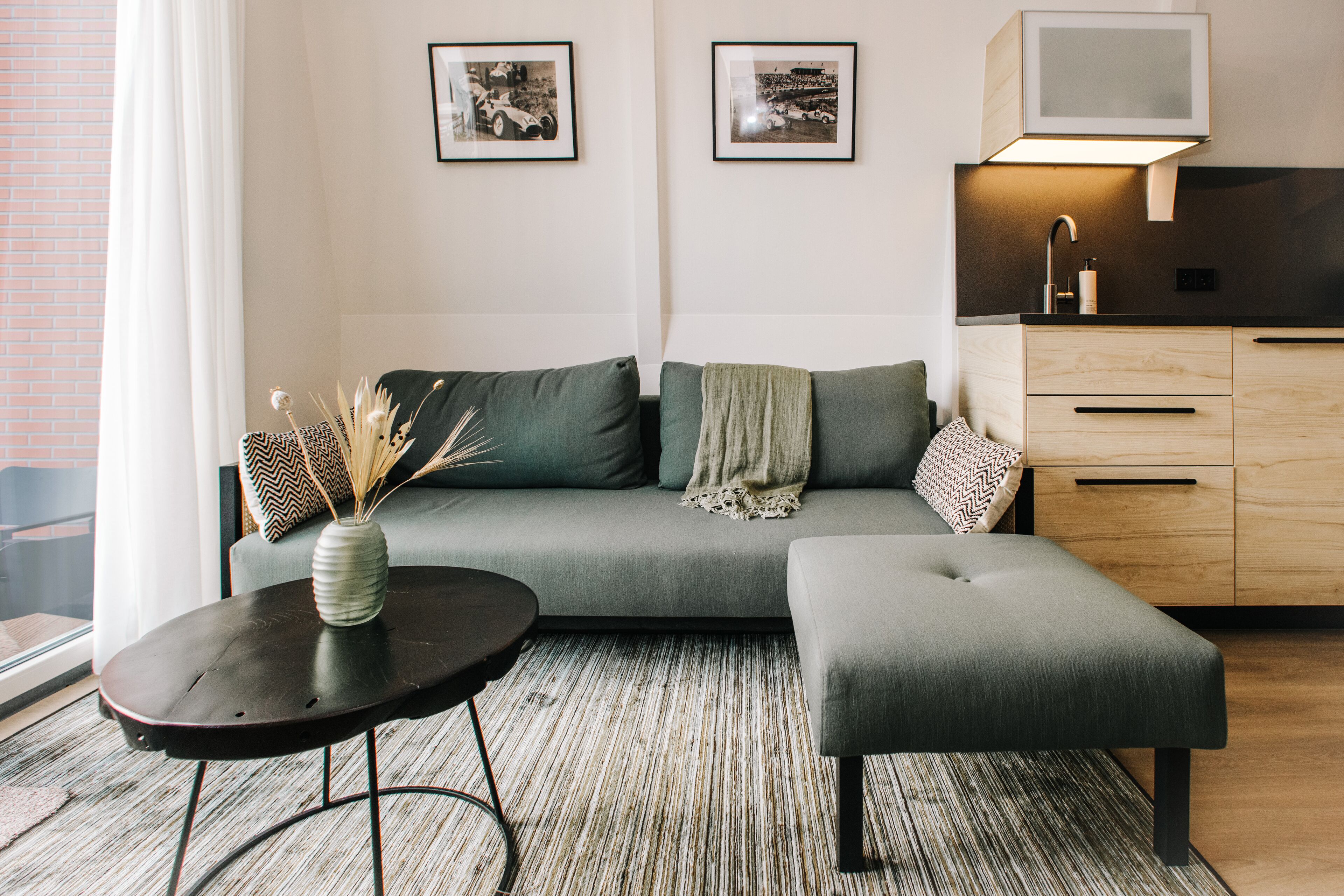 A modern living room with a grey sofa, a small round table, and a wooden cabinet.
