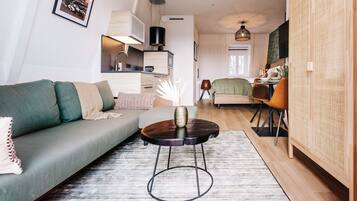 Un salon moderne comprenant un canapé, une table basse et un coin repas avec des chaises.