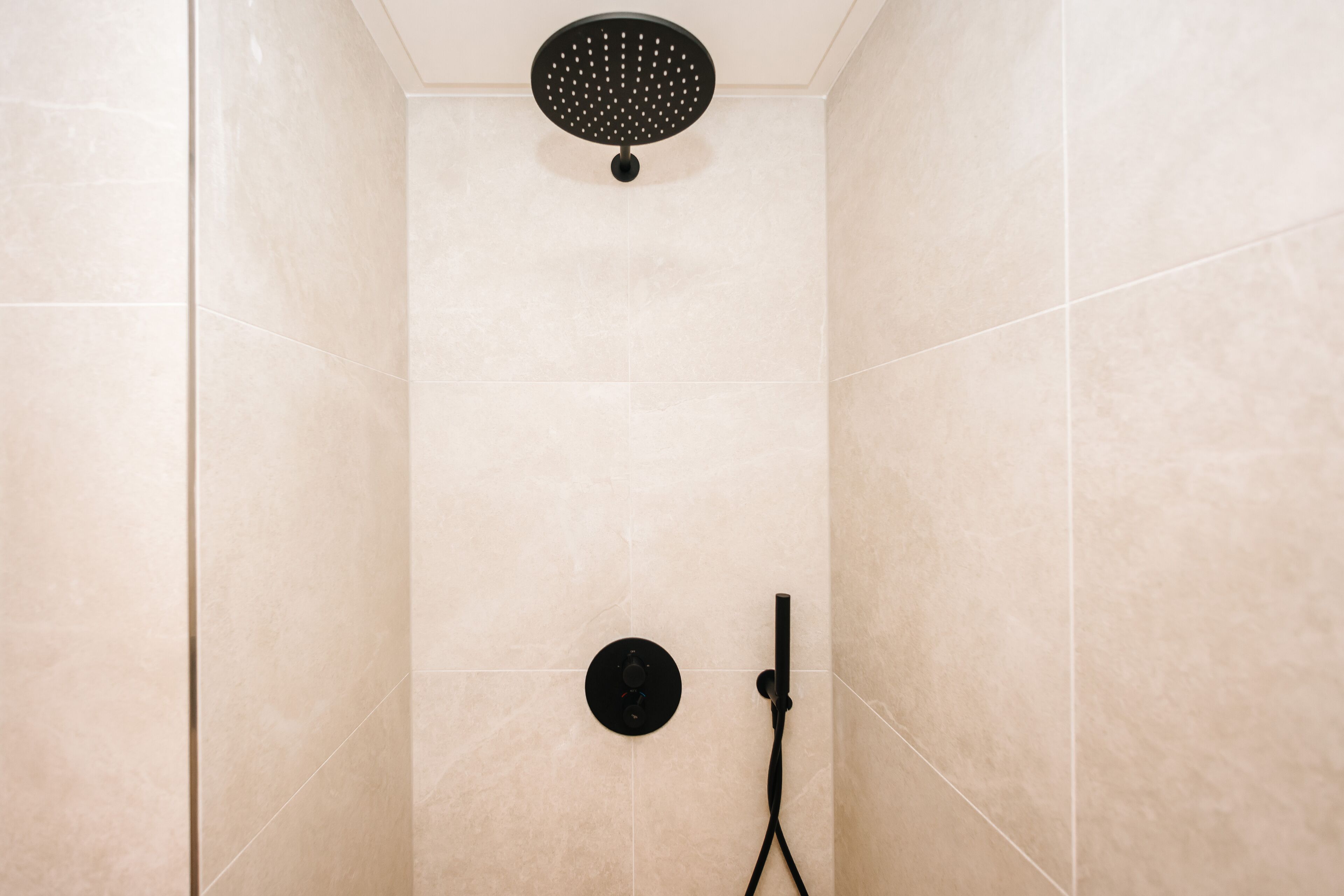 Une douche dotée d’un pommeau de douche circulaire et d’un pommeau de douche à main.
