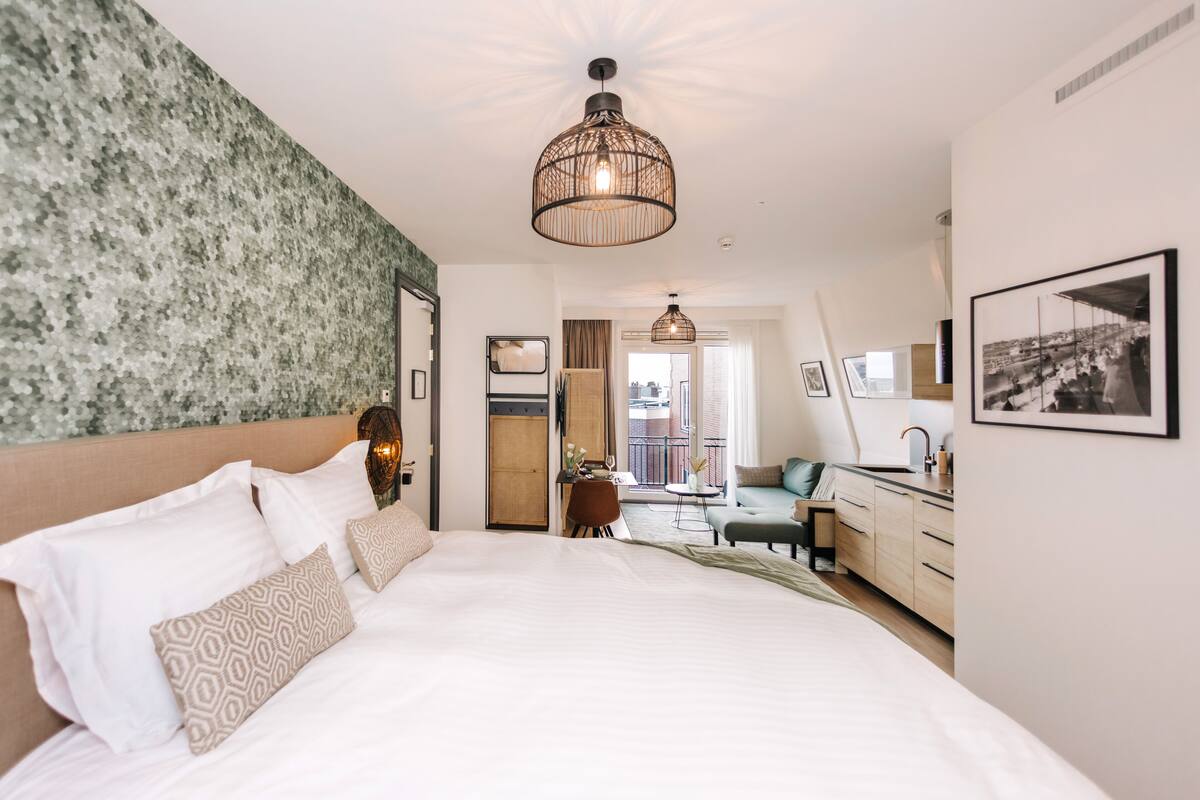 Habitación de hotel con una cama grande, un escritorio y vistas a la ciudad.