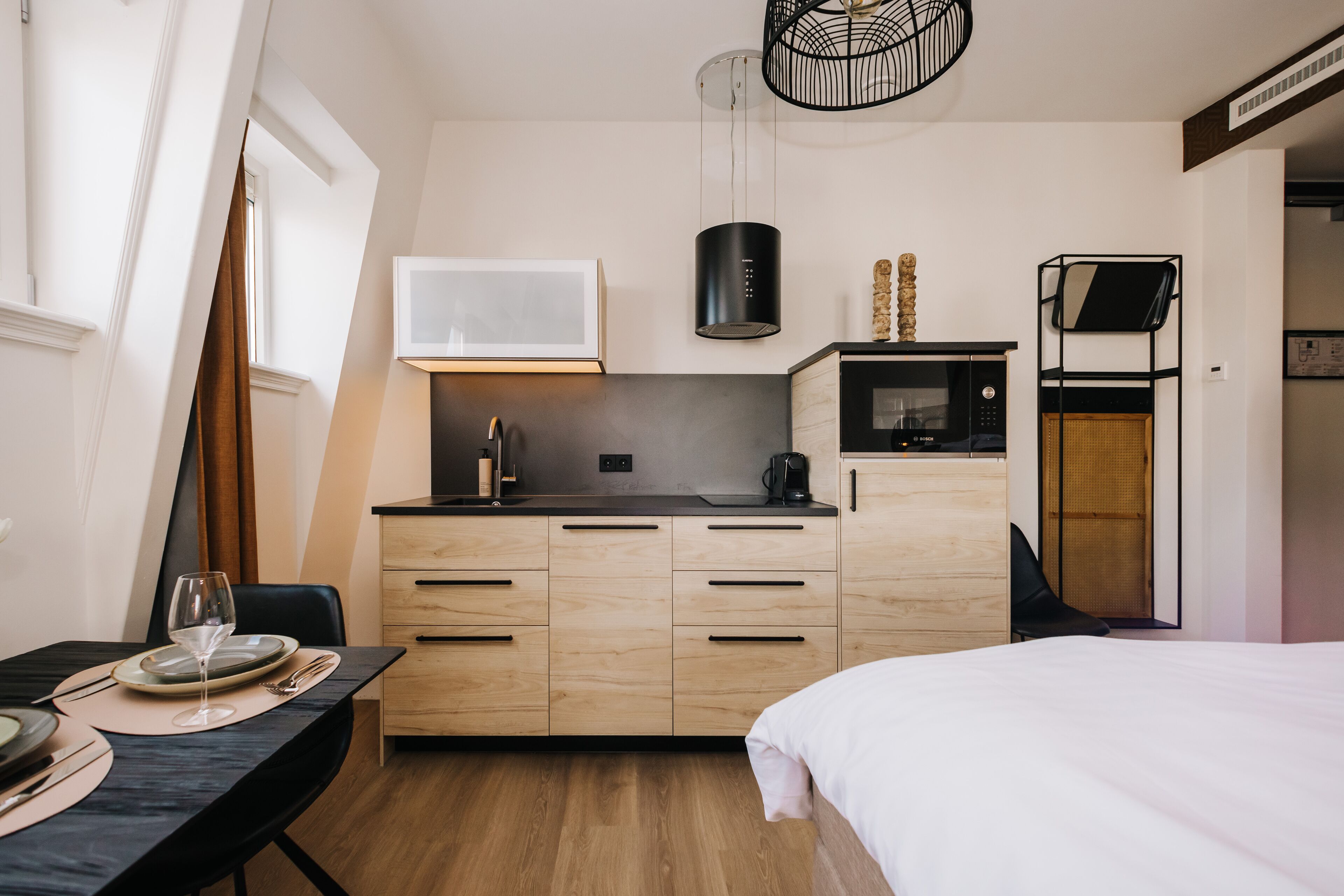 Ein kompaktes Hotelzimmer mit Küchenzeile, einem Bett, einer Essecke und Blick ins Freie.
