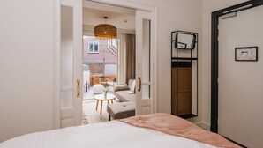 A hotel room with a bed, a small round table, a sofa, and a view of an outdoor patio area. - Boutique hotel Margretha (Zandvoort)