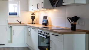 A modern kitchen with white cabinetry, a built-in oven, and a window providing natural light.