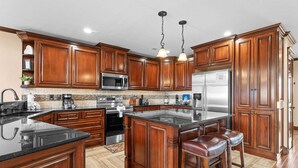 Una cocina con armarios de madera, electrodomésticos de acero inoxidable y una isla central con taburetes de bar.