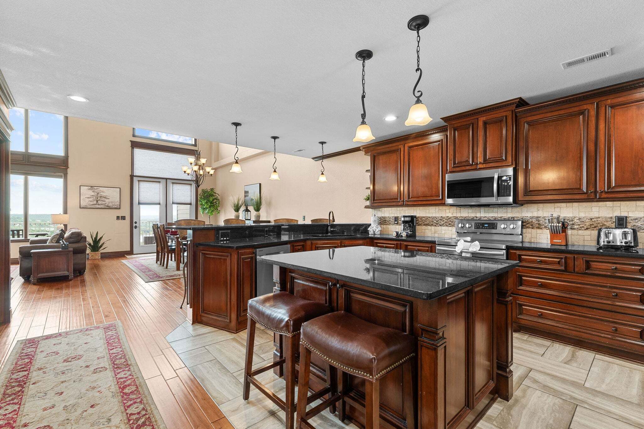 A spacious kitchen with wooden cabinets, a large island with stools, a microwave, and a coffee maker.
