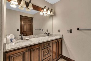 A bathroom with a large vanity, double sink, and a mirror above the sink.