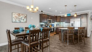 A modern kitchen with dark wood cabinets, stainless steel appliances, and a central island with bar stools. - Luxury Condo with Lake Views, Free WiFi & Minutes from Silver Dollar City (Branson)