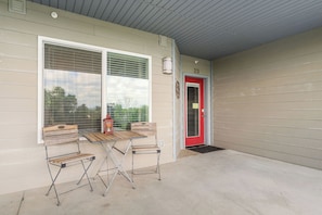 A covered outdoor area with a red door, two tables, and two chairs. - Luxury Condo with Lake Views, Free WiFi & Minutes from Silver Dollar City (Branson)