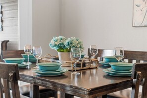 A dining table set with teal plates, wine glasses, and a centerpiece of blue flowers.