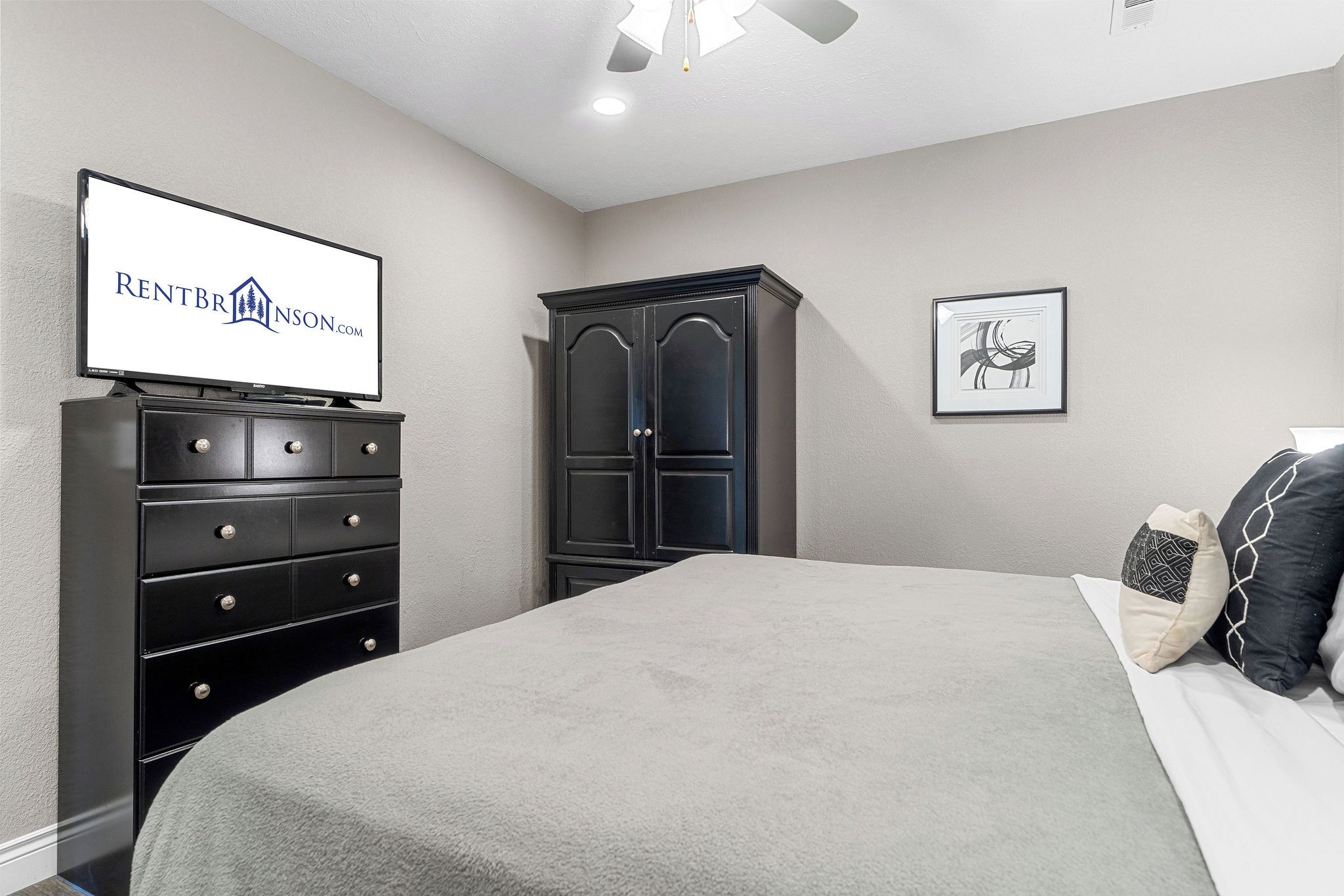 Quarto com cama, penteadeira, guarda-roupa, televisão e obras de arte.