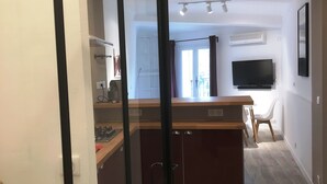 Una cucina moderna con isola centrale, zona pranzo con TV e vista all'esterno.