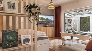 Un moderno salón con televisor, sofá, una mesita y ventana con vista a un edificio.