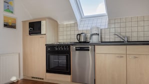 Una cocina con tragaluz, microondas, horno, lavavajillas y cafetera.
