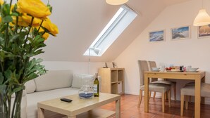 Una sala de estar acogedora con un sofá, una mesa de madera y un comedor con sillas.