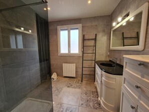 Une salle de bain avec une douche, un lavabo, des toilettes, une fenêtre et un miroir.