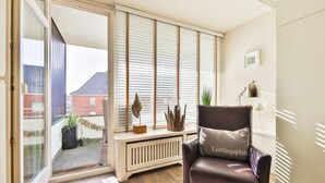 A modern living room with a brown leather chair, a radiator, and a window with blinds. - The Sunny Side - Westerland (Westerland)