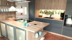 A modern kitchen with a central island, built-in appliances, and a backsplash with greenery.
