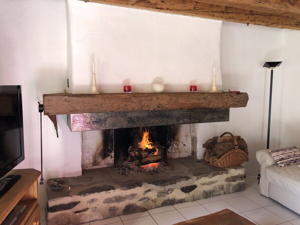 A fireplace with a stone hearth, a wooden mantel, and a television on a wooden stand to the left. - Mountain Village House for Rent, 90 m² (AZET)