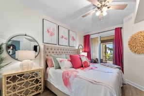Quarto com cabeceira estofada, espelho redondo, mesa de cabeceira com design geométrico e colcha de cama com tema de flamingo rosa.