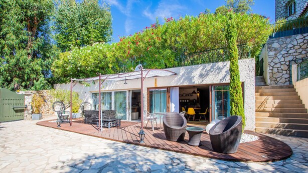 A patio area with stone flooring, wicker furniture, and a covered seating area with a view of the interior. - VILLA JUSTINE VI4239 By Riviera Holiday Homes (Mandelieu-la-Napoule)