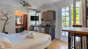 A hotel room with a bed, a desk, a kitchenette, a TV, and a bathroom. - VILLA JUSTINE VI4239 By Riviera Holiday Homes (Mandelieu-la-Napoule)