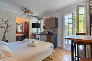 Ein Hotelzimmer mit Bett, Schreibtisch, Küchenzeile, Fernseher und Bad.