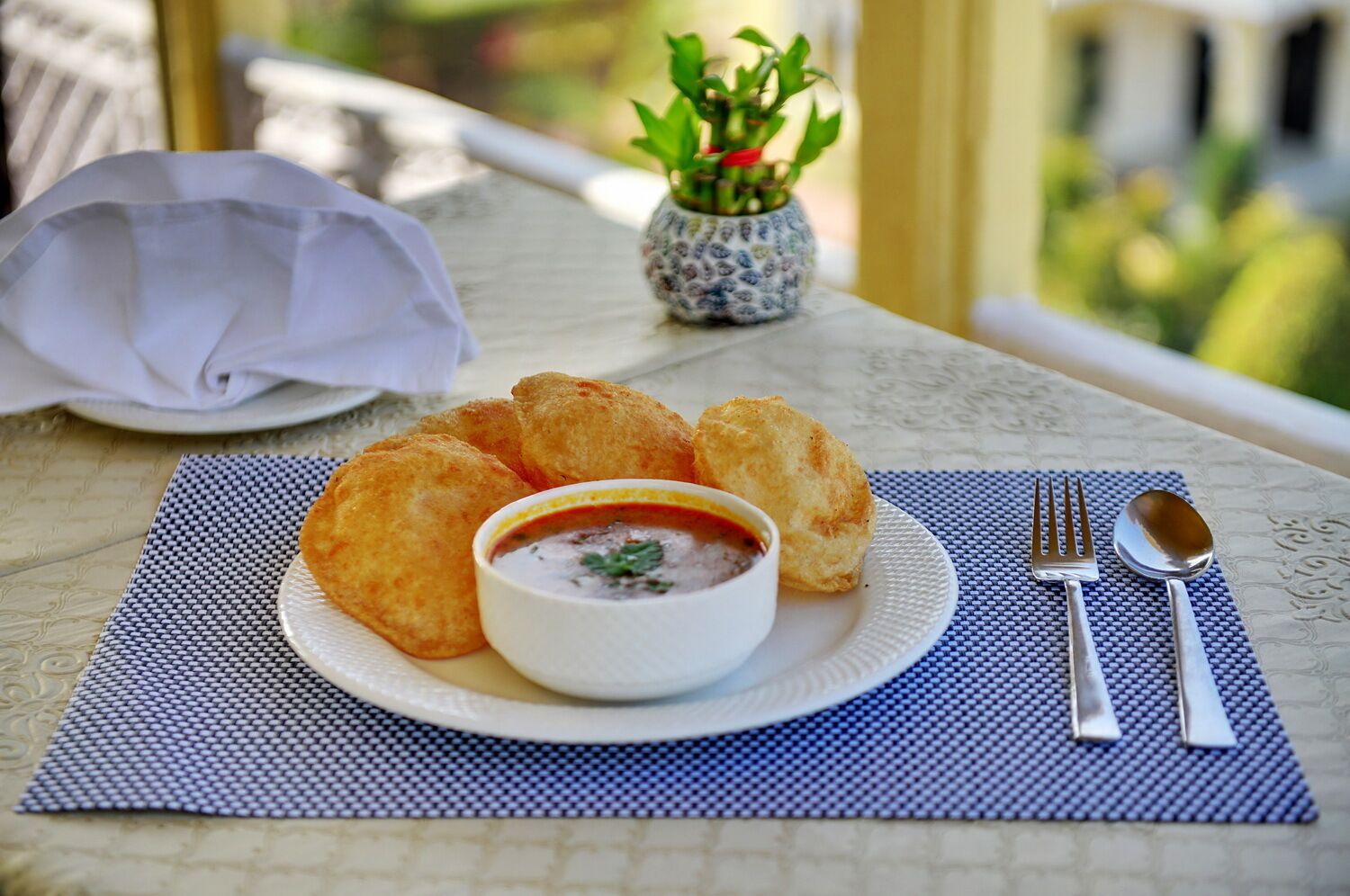 A plate of food with a bowl of soup and bread on a table with a placemat.