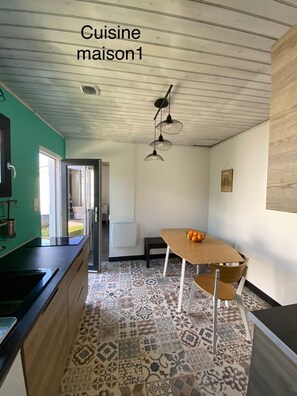 A kitchen with a wooden table, a bowl of fruit, and a hanging light fixture.