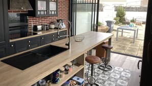 Una cocina moderna con una isla grande, armarios negros y una pared de ladrillo.