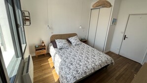 Un dormitorio con cama, mesitas de noche, armario y lámpara colgante.